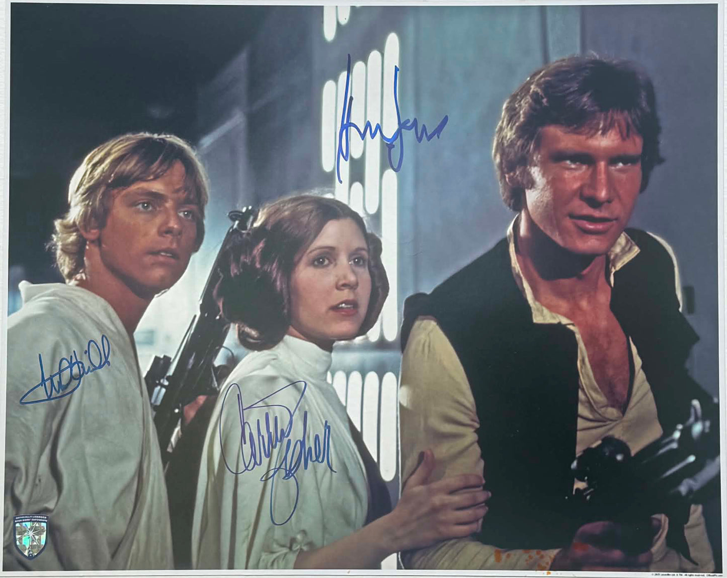 
                  
                    Harrison Ford as Han Solo, Carrie Fisher as Princess Leia, & Mark Hamill as Luke Skywalker in Star Wars: A New Hope (Official Pix Lightsaber Shield) Signed 11x14 Photo
                  
                