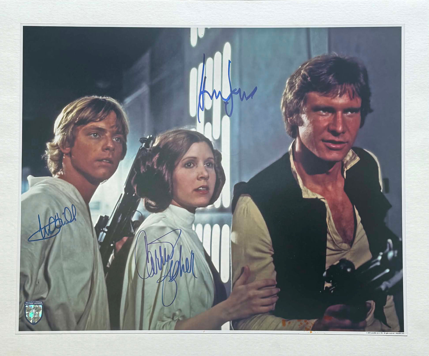 
                  
                    Harrison Ford as Han Solo, Carrie Fisher as Princess Leia, & Mark Hamill as Luke Skywalker in Star Wars: A New Hope (Official Pix Lightsaber Shield) Signed 11x14 Photo
                  
                